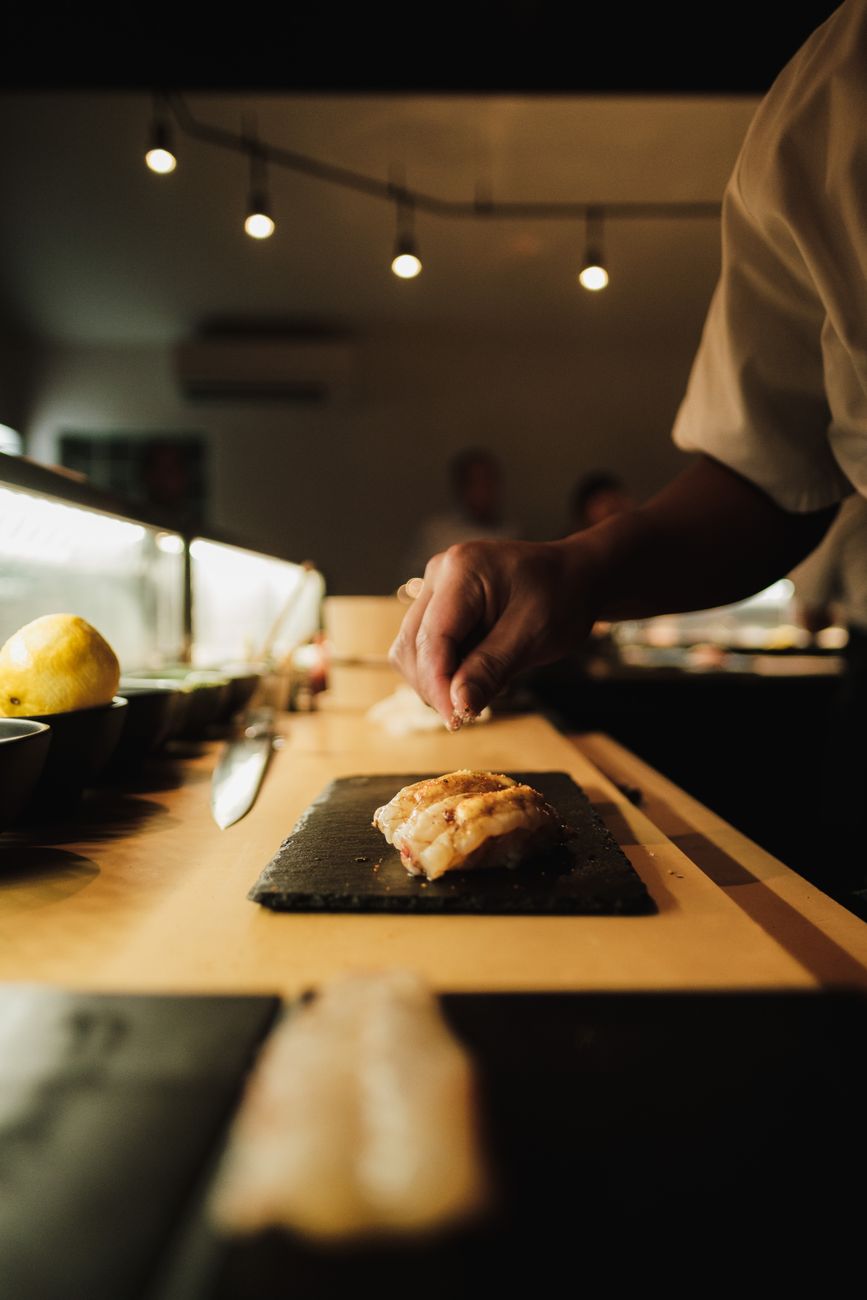 Sushi majster pripravuje nigiri za pultom v Sakurao